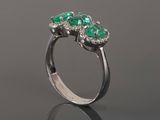 a close up of a ring with three emerald stones on it