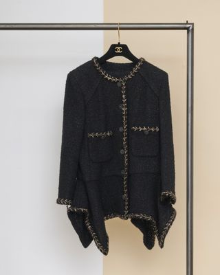 une veste noire suspendue à un cintre devant un mur beige