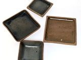 three small square dishes sitting on top of a white surface