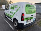 a white van parked in a parking lot with a green sign on the back of it