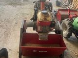 a small red tractor parked in a garage next to other vehicles
