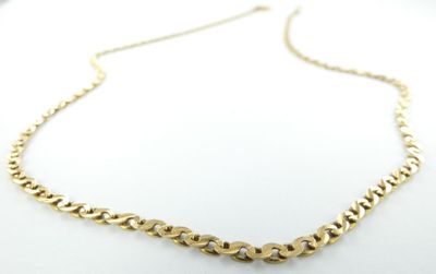 gros plan d'un collier à chaîne en or sur une surface blanche
