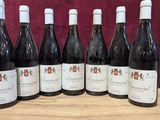 six bouteilles de vin sont alignées sur une table en bois
