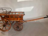a small wooden wagon with a basket on the back of it