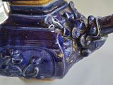 a blue vase with a bird on it on a table