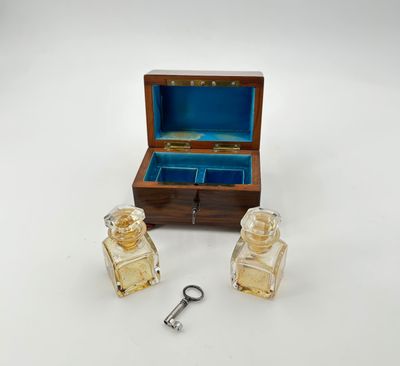 une petite boîte en bois contenant deux flacons de parfum et une clé