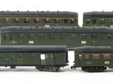 several green train cars are lined up on a white surface