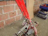 a red pipe cutter sitting on the ground next to a brick wall