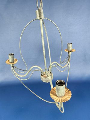une image représentant un lustre en métal avec trois bougies et une fleur
