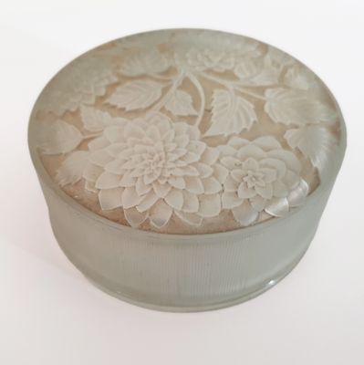 a small round box with a flower design on it