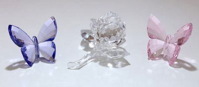 trois papillons en cristal posés sur une surface blanche