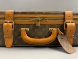 a brown and tan suitcase with a tag on it