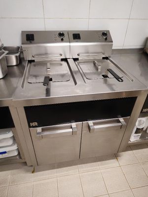 un plan de travail en acier inoxydable sur lequel sont posées deux friteuses