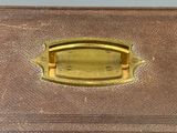 une valise marron munie d'une poignée dorée