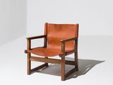 un fauteuil en cuir marron posé sur un sol blanc
