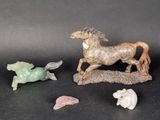 three figurines of horses and a fish on a black surface