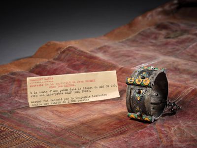 un petit bracelet en forme de chouette sur lequel repose une carte de visite