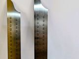 two metal rulers on a white surface next to each other
