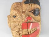 une image représentant un masque en bois aux traits rouges et noirs