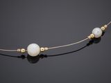 a white pearl necklace with gold beads on a black surface