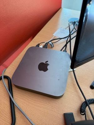an apple computer sitting on a desk with a red chair