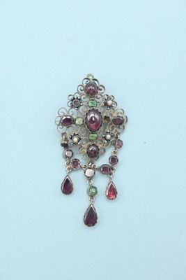 a close up of a silver broochle with red and green stones