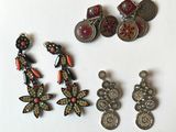 three pairs of earrings and a coin are sitting on a white surface