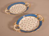 two blue and white plates with flowers on them sitting on a table