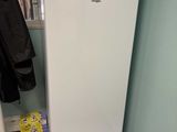 a white refrigerator in the corner of a room with a coat rack