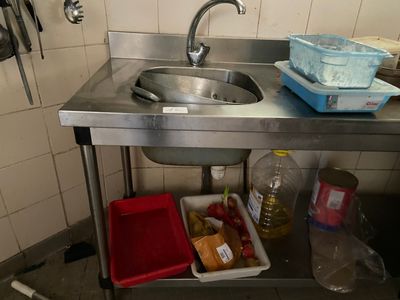 a sink in a small kitchen with a lot of food on the counter