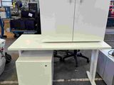 a desk with a cabinet and a chair in a warehouse