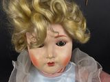 a small doll with blonde hair and a white dress