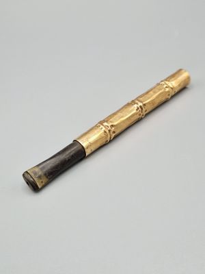 un stylo noir et doré posé sur une table blanche