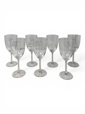 several empty wine glasses lined up in a row on a white surface