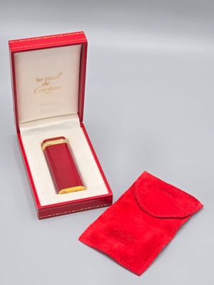 une image représentant une boîte rouge contenant un briquet plaqué or