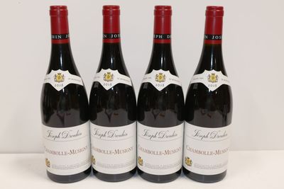 quatre bouteilles de vin rouge sont alignées sur une table