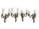 four antique brass wall sconces with white candles on them