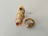 pair of gold rings with green and red stones on a white surface