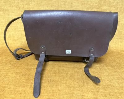 un sac en cuir marron muni d'une bandoulière, sur fond jaune