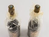 two bottles of wine wrapped in plastic wrap on a white surface