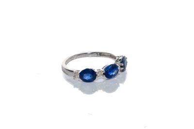 un gros plan d'une bague ornée de pierres bleues sur un fond blanc