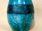 un vase bleu posé sur une table à fond blanc