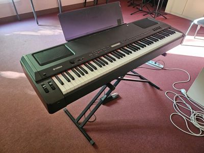 a keyboard and a laptop on a stand in a room