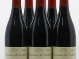 quatre bouteilles de vin rouge sont alignées sur une surface blanche