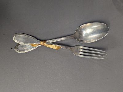 deux cuillères et une fourchette en argent sur une surface grise