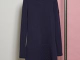 a dress hanging on a rack in front of a pink wall