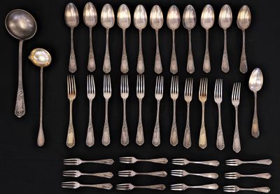 a lot of silver spoons and forks on a black table