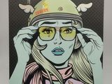 un tableau représentant une femme portant un casque et des lunettes, posé sur un chevalet