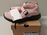 des chaussures roses à semelles noires posées sur une boîte, sur une surface blanche