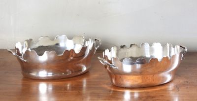 une paire de bols plaqués argent posés sur une table en bois, avec un mur blanc en arrière-plan